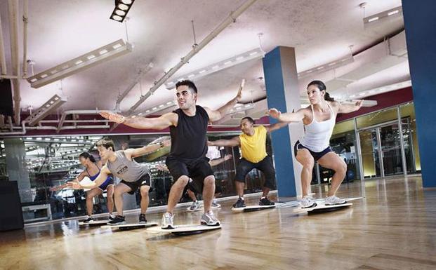 Varias personas practican deporte en un gimnasio. 