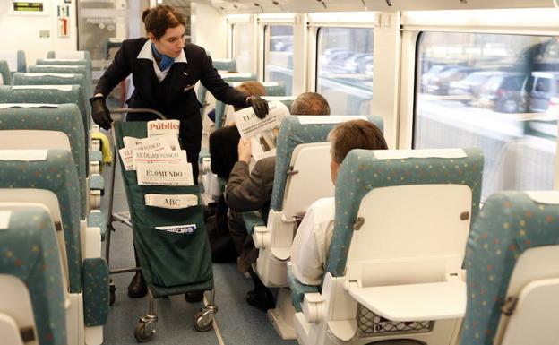 Unas azafatas ofrecen periódicos y comida a los pasajeros del tren Alvia. 