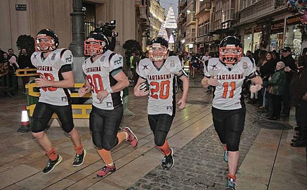 Cuatro corredores participan en la San Silvestre vestidos con una equipación de fútbol americano.