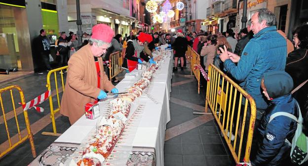 Cientos de personas esperan en cola para hacerse con un trozo de roscón de Reyes, anoche, en la calle Corredera. 