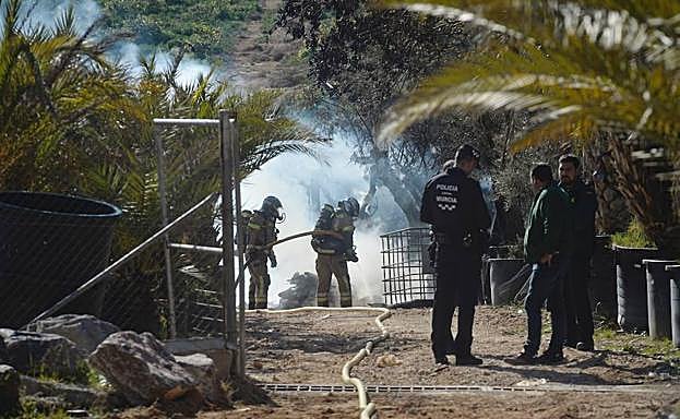 Dos bomberos refrescan el terreno quemado. 