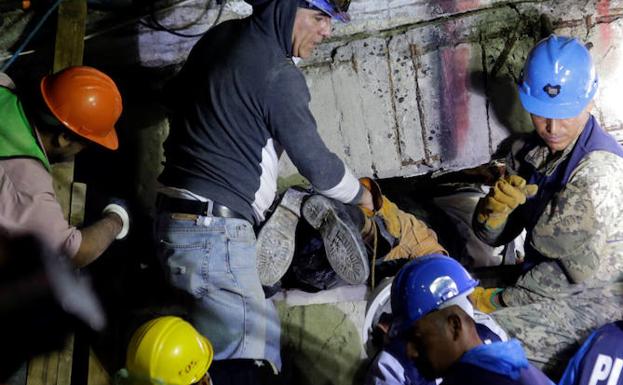 Epicentro. Uno de los rescatadores se cuela entre los escombros sujeto por sus compañeros.