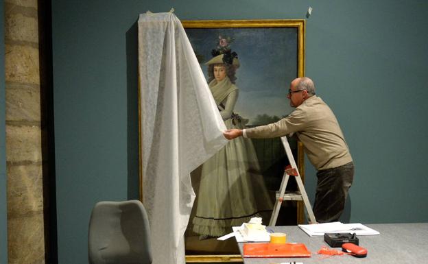 Un operario, ayer en la sala de exposiciones del Almudí, descubriendo la pieza 'Quinta duquesa de Berwick', del pintor neoclásico José Maea.
