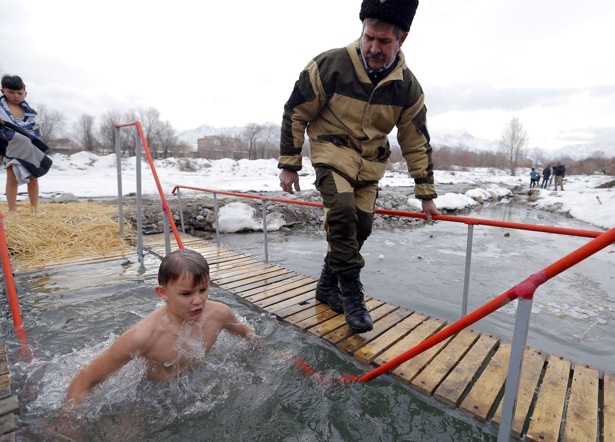 Varias personas se dan un baño en las aguas heladas de un lago para celebrar la Epifanía, cerca de la localidad de Vorontsovka, Biskek (Kirguistán). Los fieles creen que darse un chapuzón en aguas bendecidas fortalece cuerpo y espíritu.