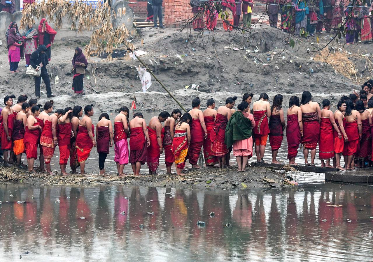 Devotos toman un baño sagrado en el río Hanumante durante el último día del Festival Madhav Narayan en Bhaktapur (Nepal). El Madhay Narayan se celebra durante un mes completo en el que se toman baños sagrados para lavar los pecados y se estudia el libro Swasthani. La veneración a la diosa Swasthani, una festividad que solo se conmemora en Nepal, es única en cada pueblo, con celebraciones y tradiciones diferentes.