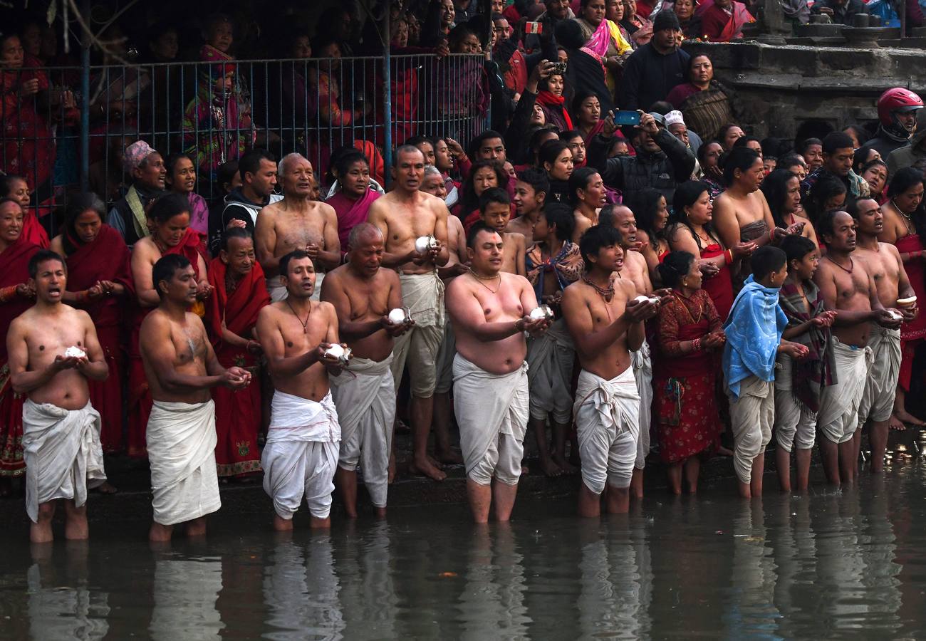 Devotos toman un baño sagrado en el río Hanumante durante el último día del Festival Madhav Narayan en Bhaktapur (Nepal). El Madhay Narayan se celebra durante un mes completo en el que se toman baños sagrados para lavar los pecados y se estudia el libro Swasthani. La veneración a la diosa Swasthani, una festividad que solo se conmemora en Nepal, es única en cada pueblo, con celebraciones y tradiciones diferentes.