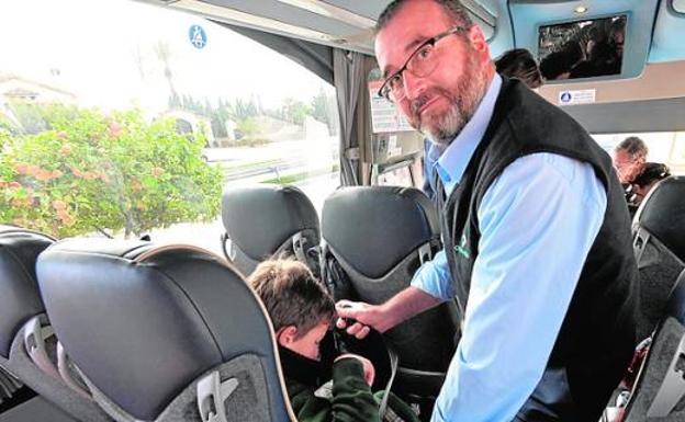 Un conductor enseña a un niño cómo abrocharse el cinturón. agm
