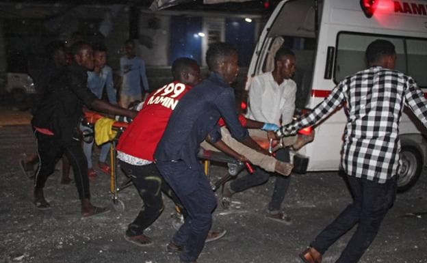 Varias personas trasladan a un herido a una ambulancia en el lugar donde explotó el camión bomba.