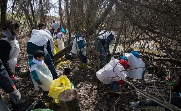 Niños y adultos limpian de basura la orilla de un río, en una fotografía de archivo.