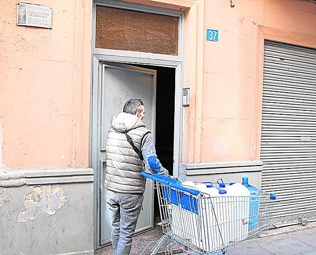 Un inquilino lleva garrafas a una fuente, para llenarlas. 