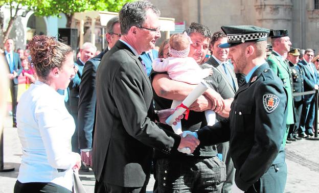 El policía local Adrián Murcia estrecha la mano del alcalde en presencia de la pequeña Thais y sus padres. 