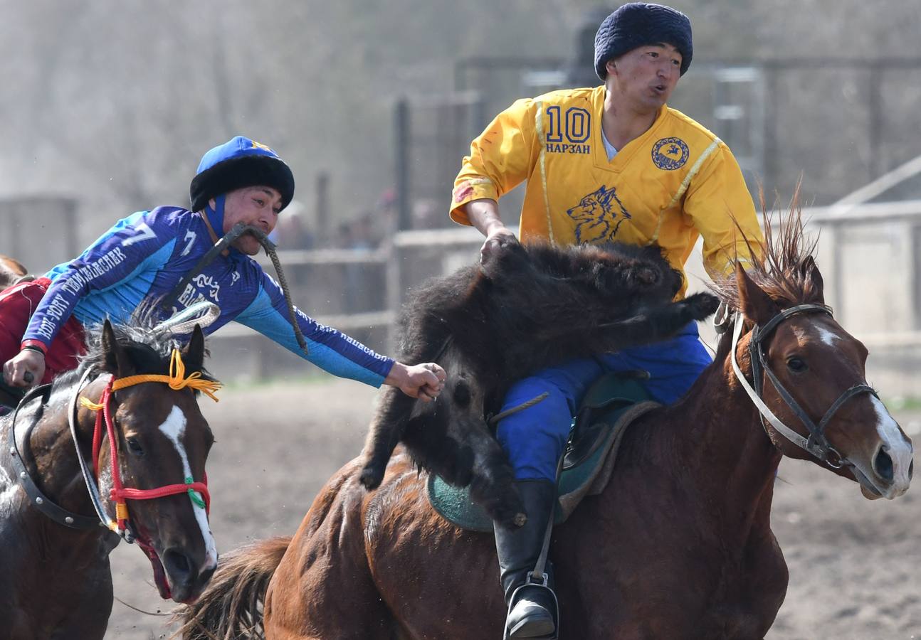 Varios jinetes participan en la competición tradicional kirguizistana llamada 'Kok-Boru', o arrastre de la cabra, con motivo de las celebraciones del Año Nuevo en el calendario solar persa, en Biskek (Kirguizistán). En el Kok-Boru los jugadores deben agarrar el cuerpo de una cabra desde el suelo mientras montan a caballo e intentar anotar un tanto al dejarlo sobre la portería del contrario.