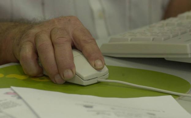 Un hombre utiliza el ratón de su ordenador en una oficina.