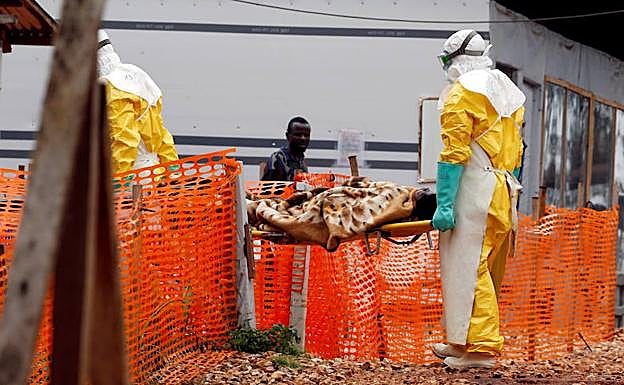 Dos sanitarios portan a un enfermo de ébola, en un centro de la República Democrática del Congo