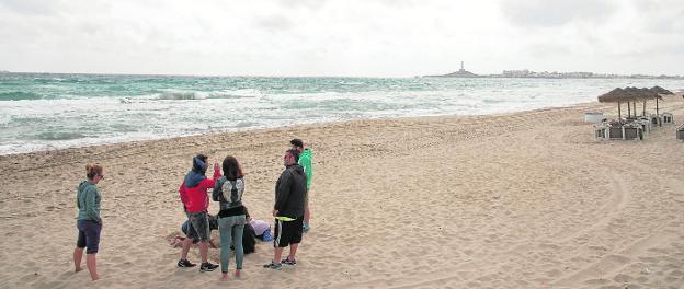 Un grupo de personas hace frente en la playa de Las Sirenas, en La Manga, al aire y a los nubarrones que ayer comenzaron a asomar por la costa. 