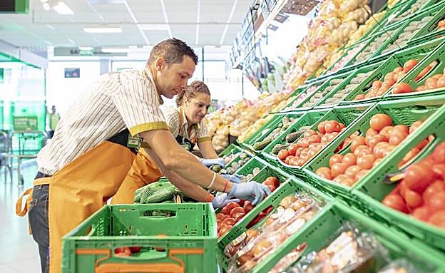 Dos empleados colocan hortalizas en un supermercado de Mercadona. 