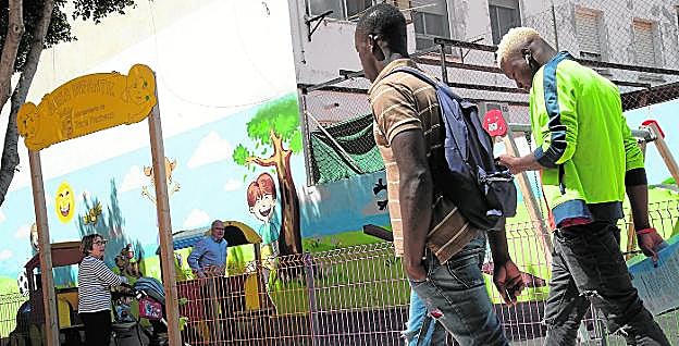 Dos inmigrantes pasan por un parque infantil del centro de Torre Pacheco, ayer por la mañana, después de hacer gestiones en el Ayuntamiento. 