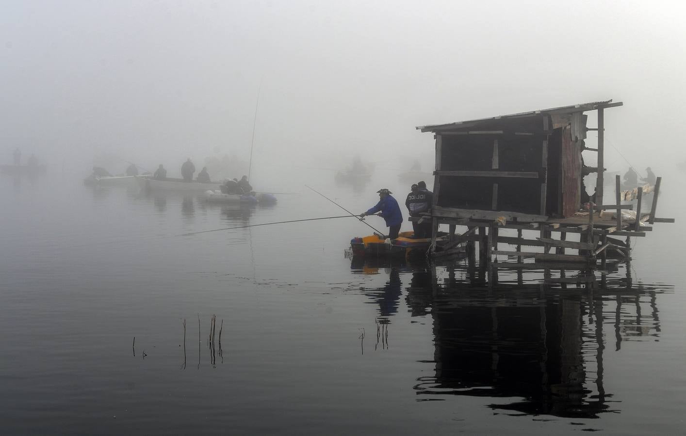 Varias personas pescan bajo la niebla en las orillas del lago Dojran, Macedonia. El lago Dojran es una reserva natural que atrae a diferentes especies de aves debido al clima relativamente cálido y la gran cantidad de peces.