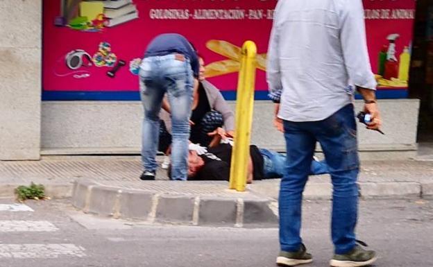 Unos vecinos tratan de socorrer al hombre tras la agresión.