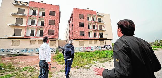 Tres vecinos observan los dos inmuebles que han estado ocupados por indigentes y que ahora utilizan pandillas de grafiteros, que también encienden hogueras. AGM