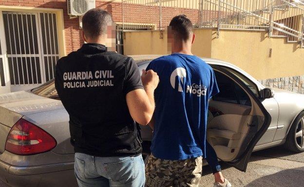 Uno de los investigadores de la Guardia Civil, conduciendo a uno de los tres sospechosos hasta el juzgado de San Javier en una foto de archivo. 