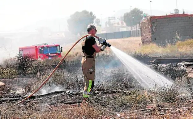 Un bombero apaga los rescoldos del fuego declarado en Sangonera la Seca. 