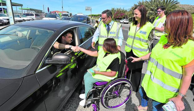 Un conductor saluda a una de las voluntarias de Aspaym que colabora en la campaña de concienciación, en presencia del delegado del Gobierno y la jefa provincial de Tráfico. 