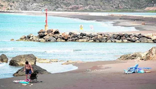 Un vecino toma el sol en la cala del Lastre, donde se permite el baño. Al fondo, la playa de San Bruno, en la que está prohibido. 