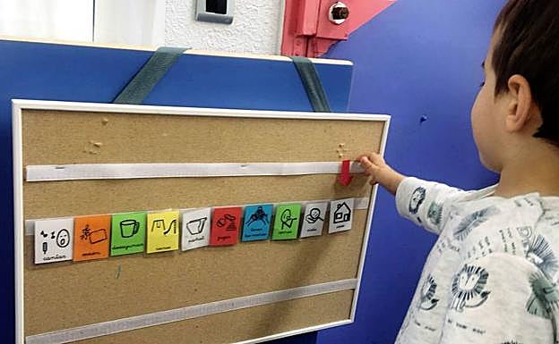 Un niño con autismo juega con pictogramas en un aula Alanda, asociación de apoyo escolar.