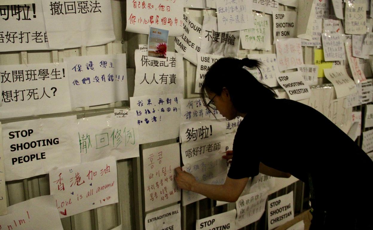 Jóvenes hongkoneses pegan carteles criticando la represión policial de las manifestaciones contra la ley de extradición a China. 