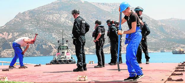 Dos de los ocho tripulantes del mercante trabajan para abrir la bodega de proa, en presencia de policías aduaneros, a su llegada al puerto de Escombreras.