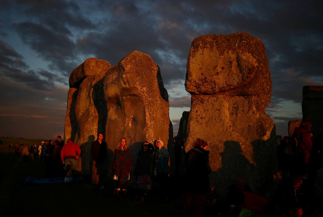 Varios entusiastas reciben el amanecer mientras participan en las celebraciones por el solsticio de verano en Stonehenge, en Wiltshire (Reino Unido). Este festival atrae anualmente a cientos de personas para celebrar el llegada del día más largo en el hemisferio norte.