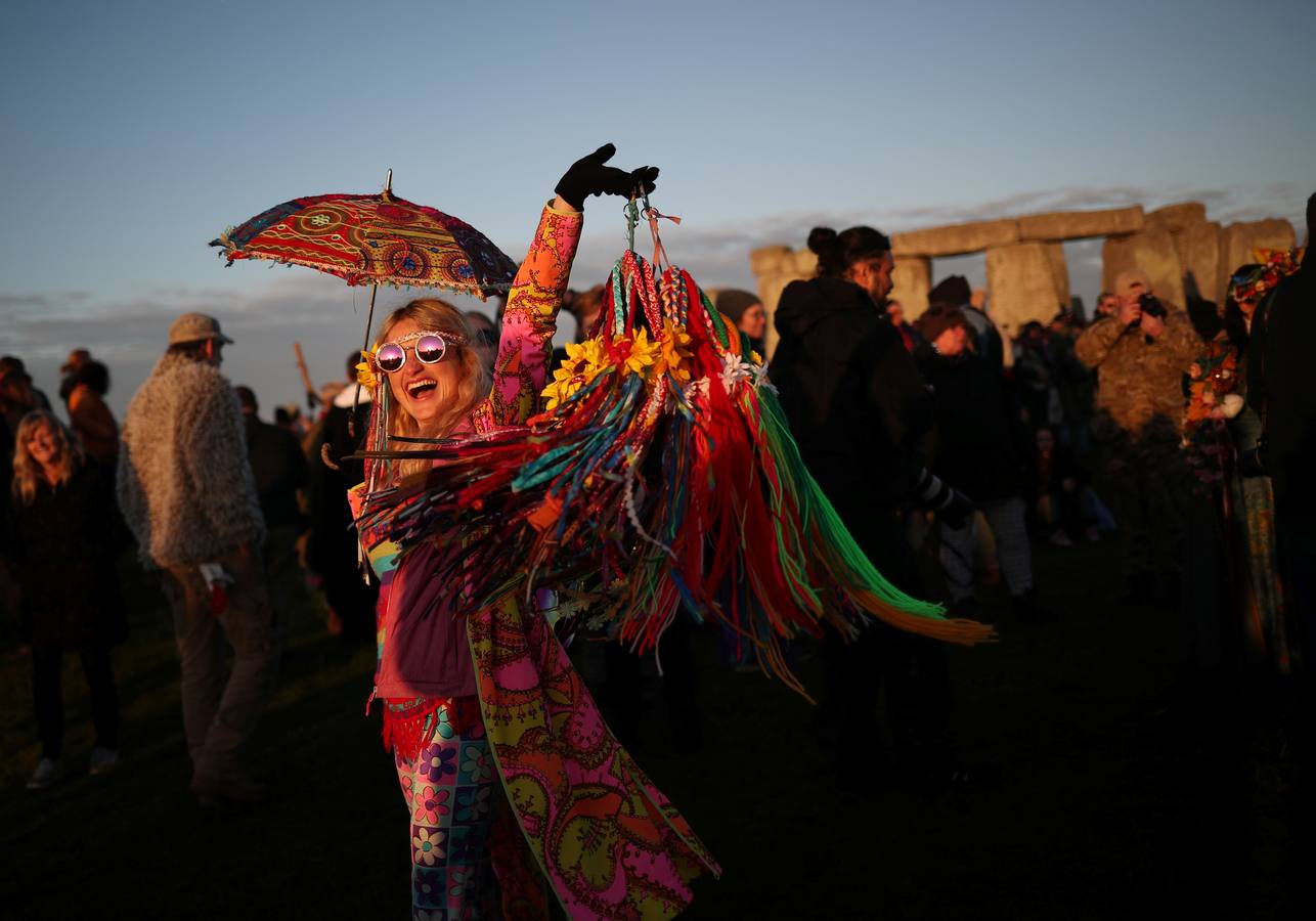 Varios entusiastas reciben el amanecer mientras participan en las celebraciones por el solsticio de verano en Stonehenge, en Wiltshire (Reino Unido). Este festival atrae anualmente a cientos de personas para celebrar el llegada del día más largo en el hemisferio norte.