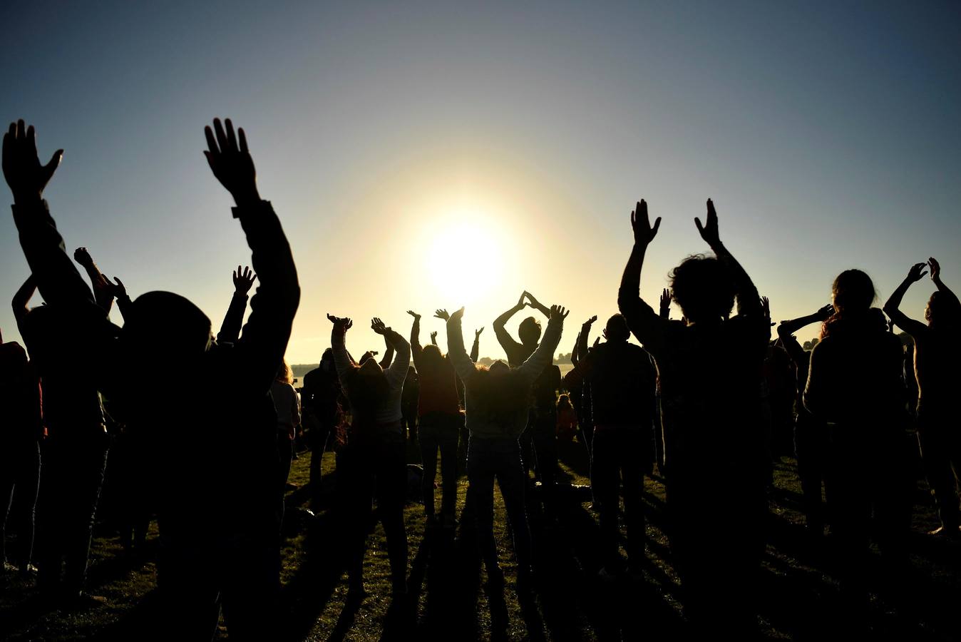 Varios entusiastas reciben el amanecer mientras participan en las celebraciones por el solsticio de verano en Stonehenge, en Wiltshire (Reino Unido). Este festival atrae anualmente a cientos de personas para celebrar el llegada del día más largo en el hemisferio norte.