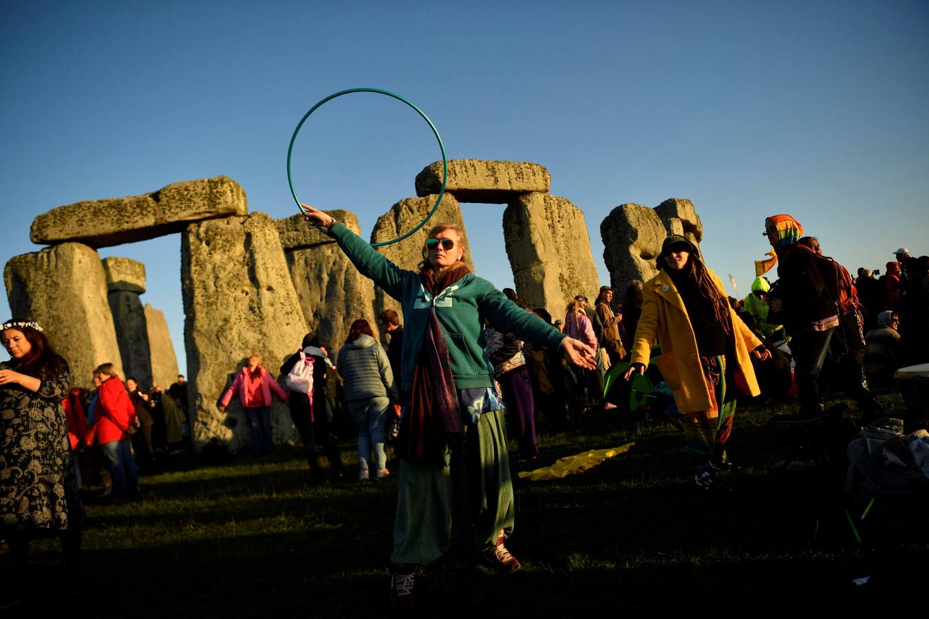 Varios entusiastas reciben el amanecer mientras participan en las celebraciones por el solsticio de verano en Stonehenge, en Wiltshire (Reino Unido). Este festival atrae anualmente a cientos de personas para celebrar el llegada del día más largo en el hemisferio norte.