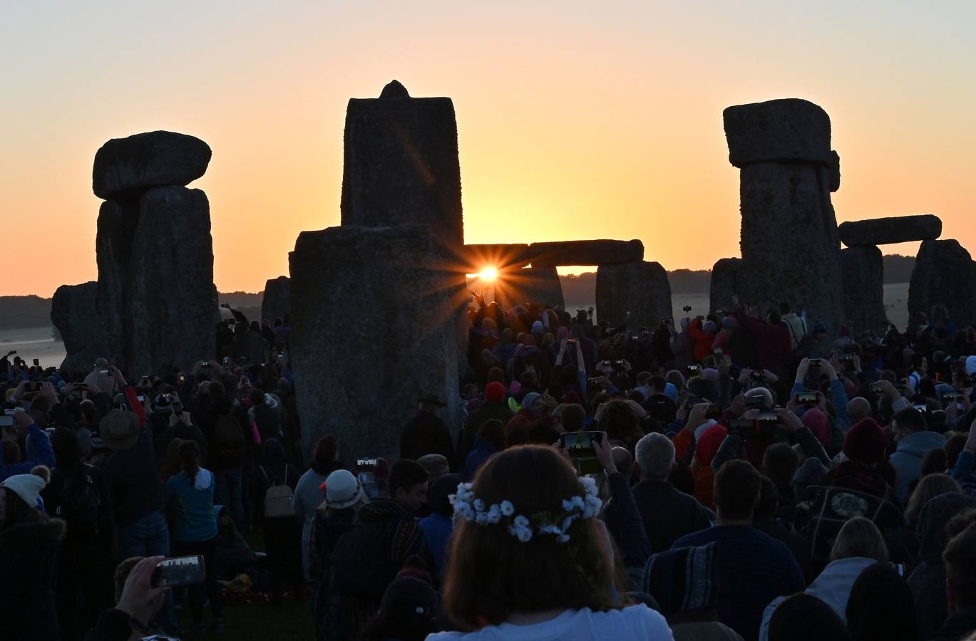 Varios entusiastas reciben el amanecer mientras participan en las celebraciones por el solsticio de verano en Stonehenge, en Wiltshire (Reino Unido). Este festival atrae anualmente a cientos de personas para celebrar el llegada del día más largo en el hemisferio norte.