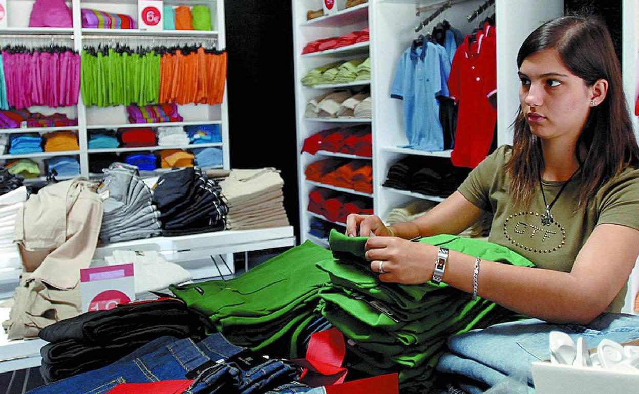 Una dependiente prepara varias prendas en una tienda. 
