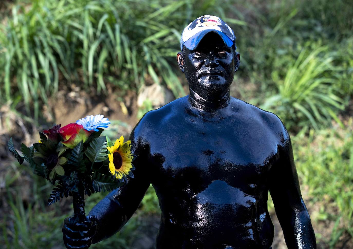 Varias personas llevan el cuerpo cubierto con aceite para cumplir con la tradición de «Los Diablitos Negros» durante una procesión en la que fieles católicos transportan la imagen de Santo Domingo de Guzmán, en Managua (Nicaragua). Como es tradición, la música pone el tono festivo y los creyentes bailan a la vez que avanzan hacia el norte de Managua, alrededor de la imagen, que es zangoloteada por los cargadores, como símbolo de alegría.