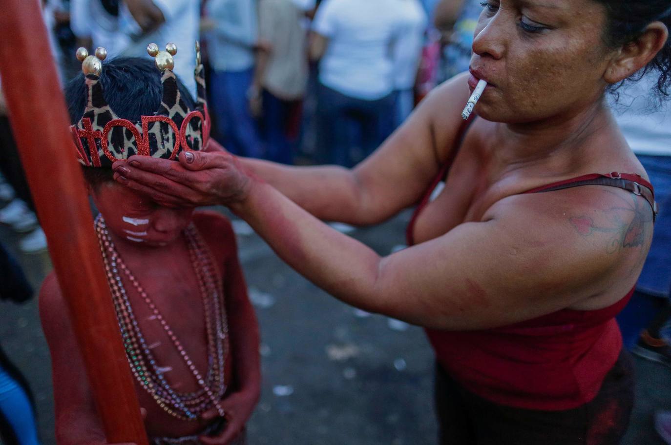 Varias personas llevan el cuerpo cubierto con aceite para cumplir con la tradición de «Los Diablitos Negros» durante una procesión en la que fieles católicos transportan la imagen de Santo Domingo de Guzmán, en Managua (Nicaragua). Como es tradición, la música pone el tono festivo y los creyentes bailan a la vez que avanzan hacia el norte de Managua, alrededor de la imagen, que es zangoloteada por los cargadores, como símbolo de alegría.