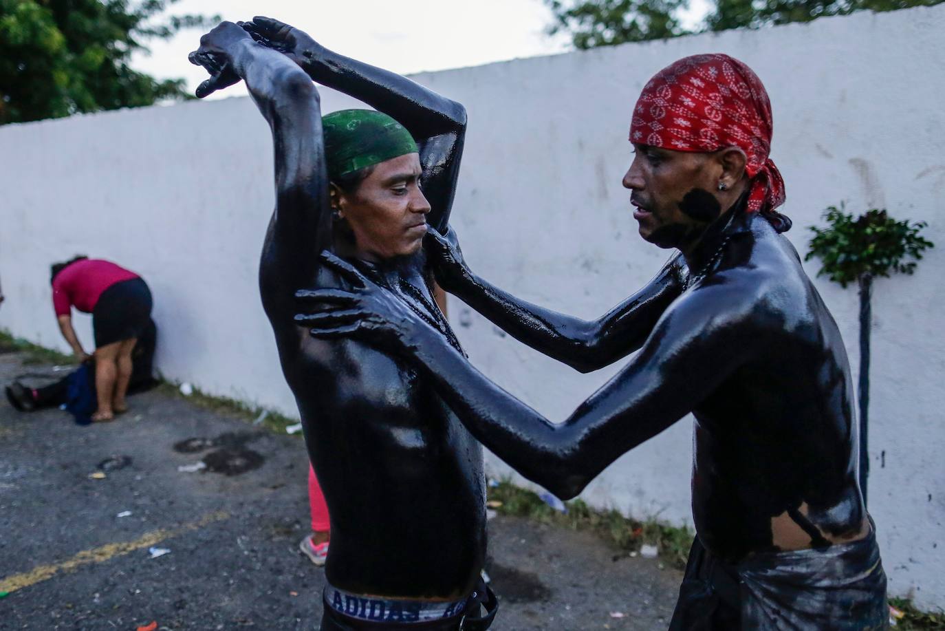 Varias personas llevan el cuerpo cubierto con aceite para cumplir con la tradición de «Los Diablitos Negros» durante una procesión en la que fieles católicos transportan la imagen de Santo Domingo de Guzmán, en Managua (Nicaragua). Como es tradición, la música pone el tono festivo y los creyentes bailan a la vez que avanzan hacia el norte de Managua, alrededor de la imagen, que es zangoloteada por los cargadores, como símbolo de alegría.