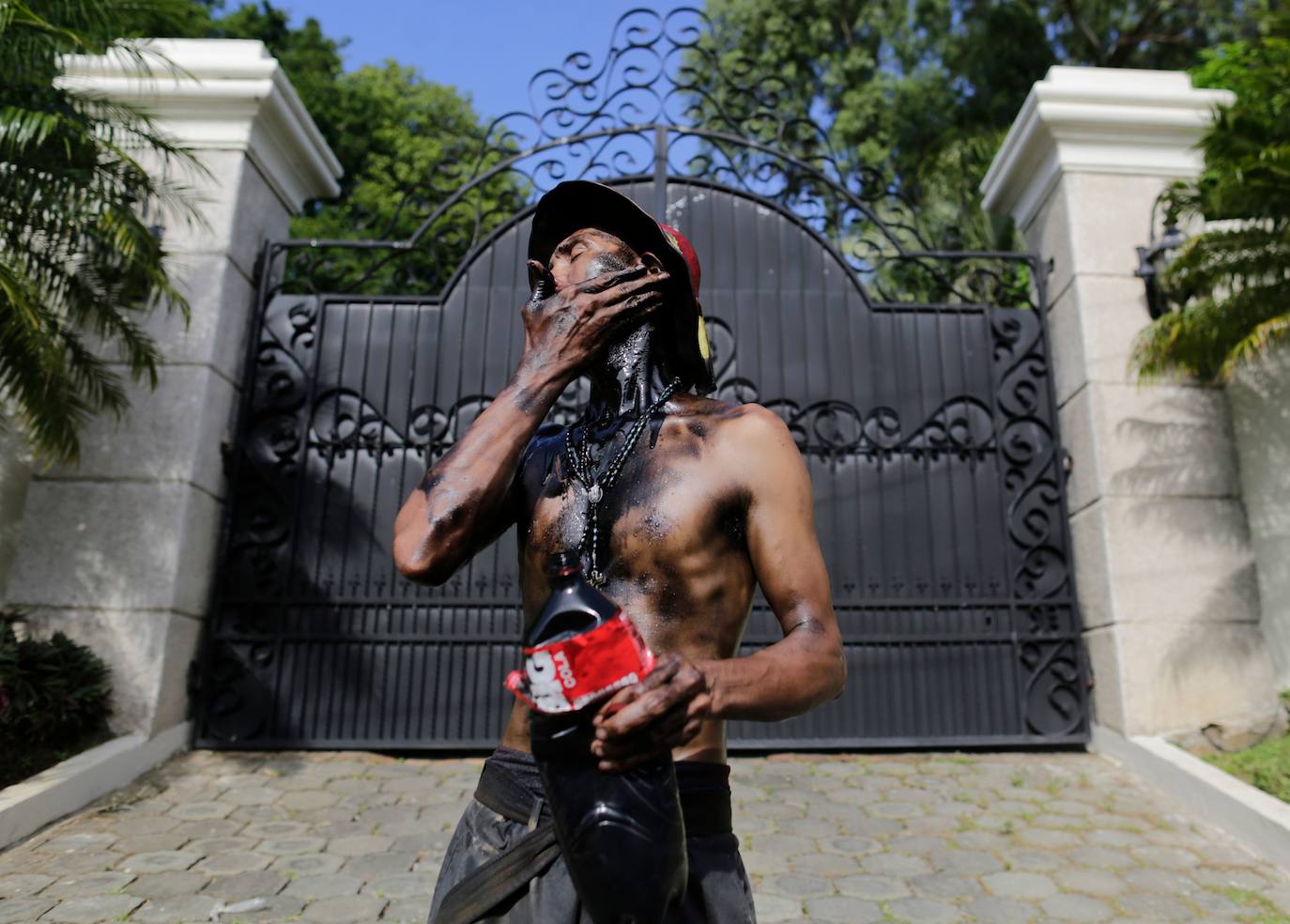 Varias personas llevan el cuerpo cubierto con aceite para cumplir con la tradición de «Los Diablitos Negros» durante una procesión en la que fieles católicos transportan la imagen de Santo Domingo de Guzmán, en Managua (Nicaragua). Como es tradición, la música pone el tono festivo y los creyentes bailan a la vez que avanzan hacia el norte de Managua, alrededor de la imagen, que es zangoloteada por los cargadores, como símbolo de alegría.