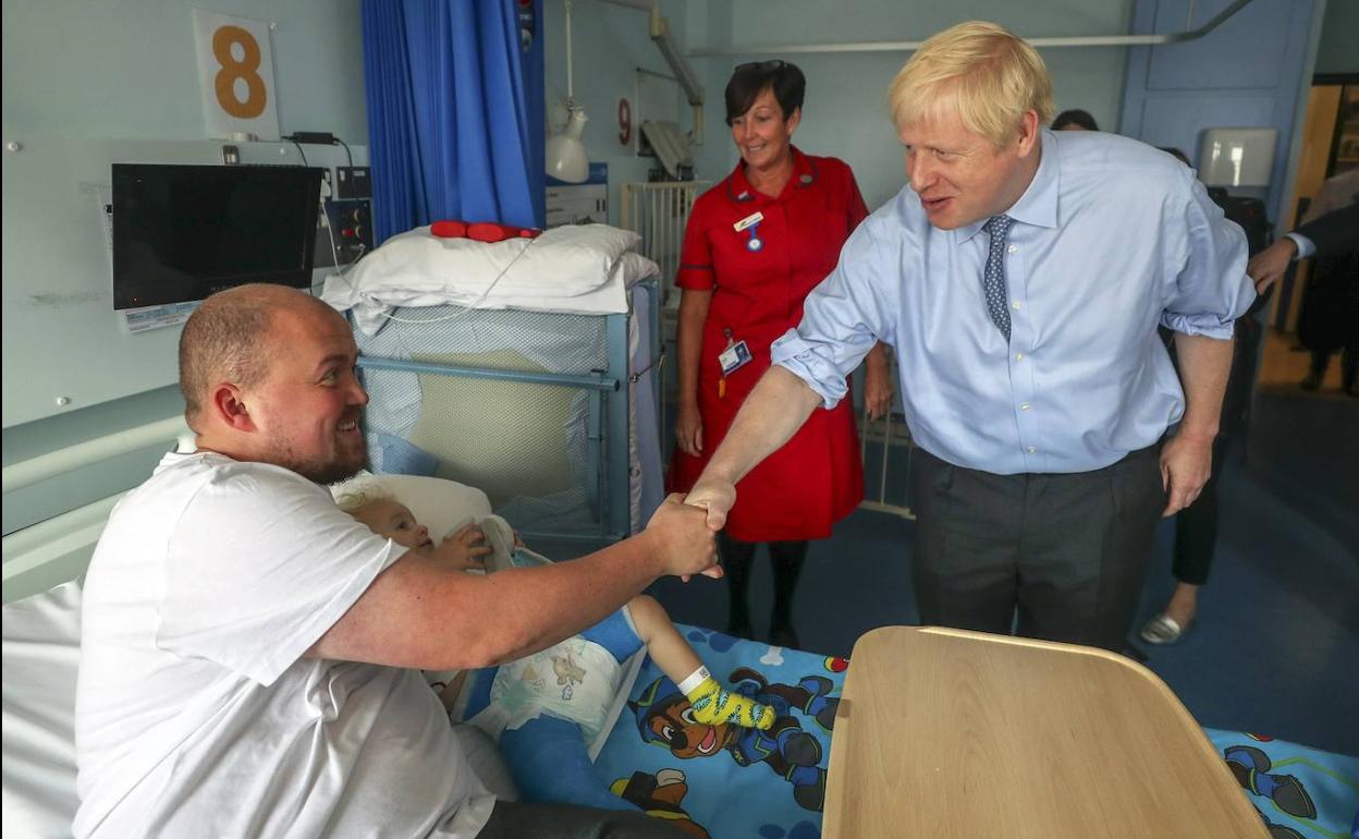 El 'premier' británico, Boris Johnson, saluda al padre de un niño ingresado en su visita al Royal Cornwall Hospital. 