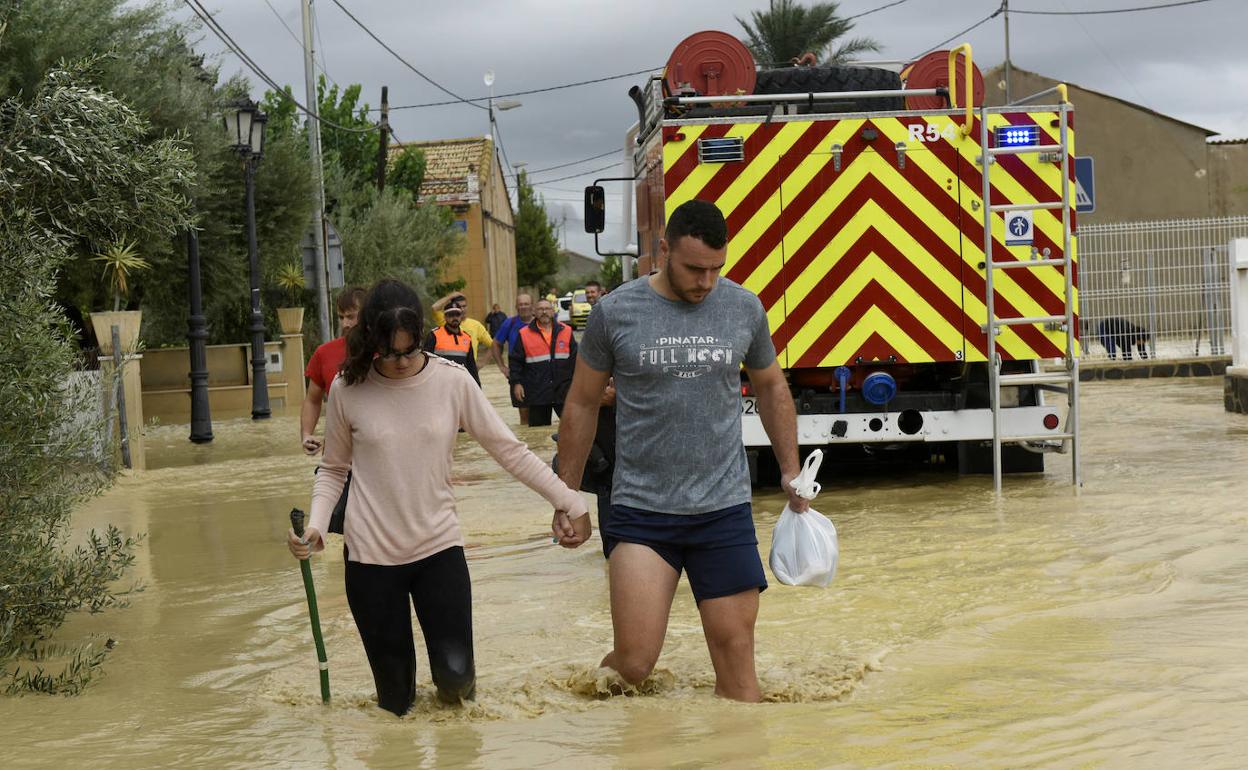 Vecinos de Alquerías, este viernes, intentando cruzar una de las calles inundadas.