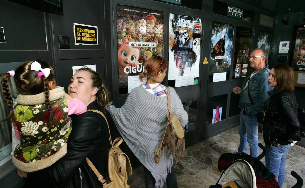 Público de diferentes edades, a la entrada de un cine.