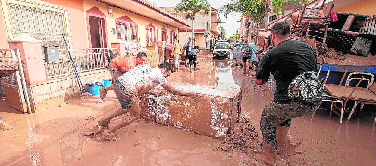 Vecinos de Los Alcázares, ayer, retiran de sus viviendas enseres arrasados por el torrente de fango. 