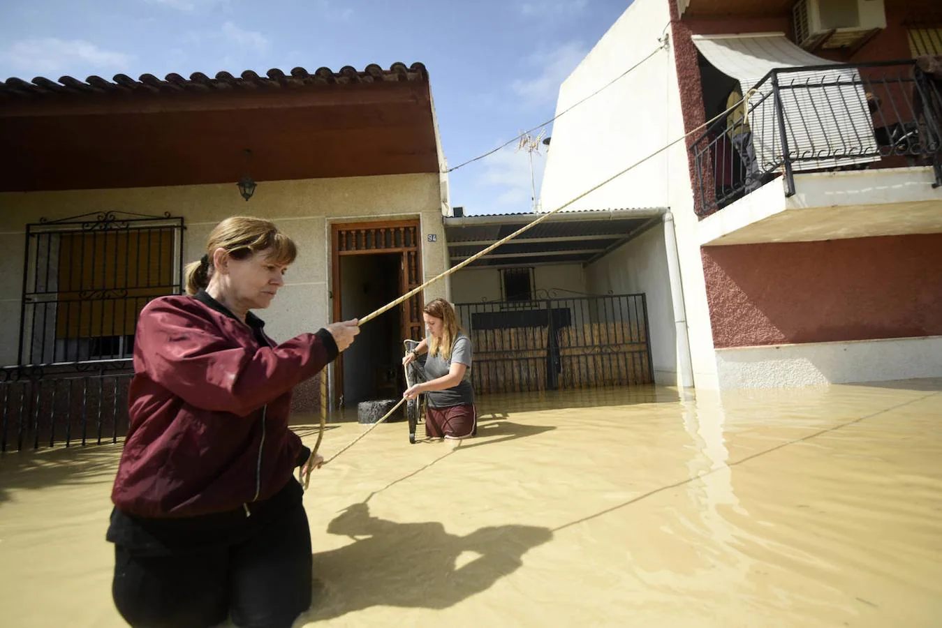 Una mujer se agarra a su balcón con una cuerda para no ser arrastrada por el agua en el camino de Carcanox, Alquerias.