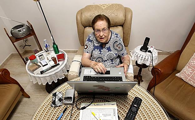 Carmen Lázaro trastea el ordenador con el que escucha a Manolo Escobar, en su salón, en Lorca.