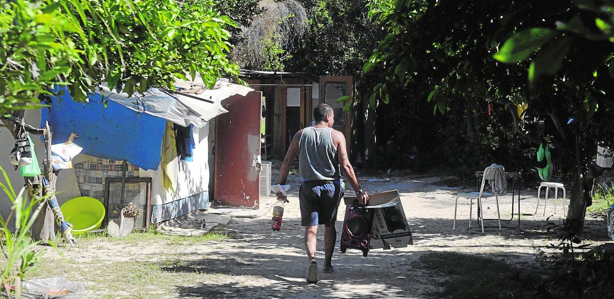 Uno de los hombres que vive en el asentamiento chabolista de La Fica entra en el poblado con enseres en la mano. 