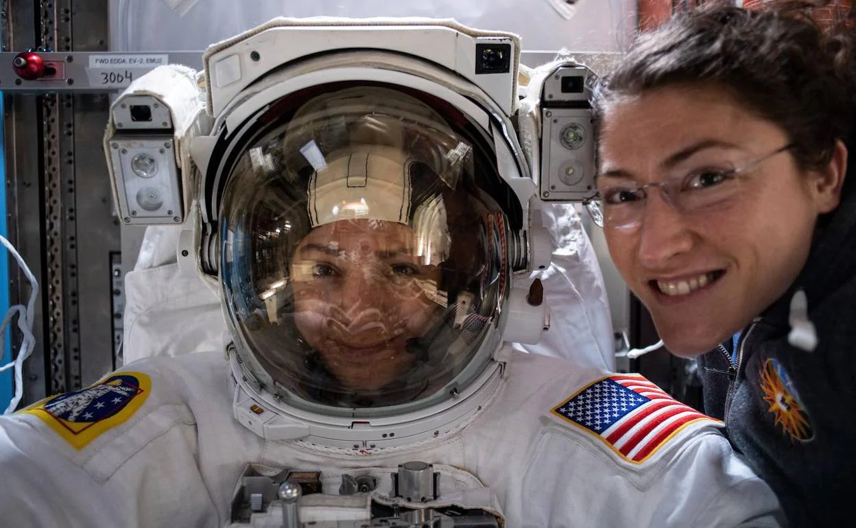 La astronauta Christina Koch (D) posa con su compañera Jessica Meir antes de realizar la primera caminata espacial 100% femenina.