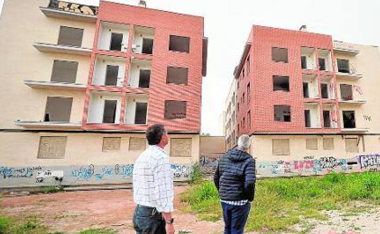 Dos vecinos observan dos inmuebles que han estado ocupados por indigentes, en una imagen de archivo.